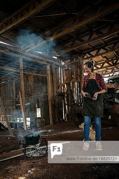 Die junge Frau in Uniform  die in einer Fabrik arbeitet und für alle mit Feuer auf dem Boden kocht