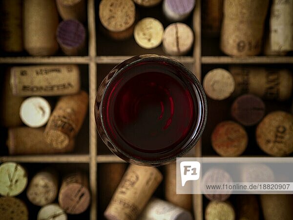 Glas Rotwein auf Flaschenkorken in einer Holzkiste  Ansicht von oben