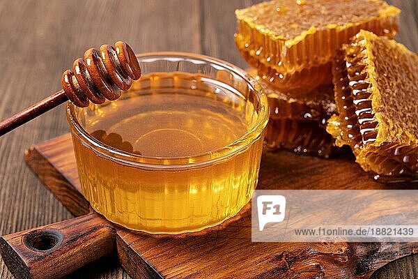 Gelber Honig und Honigwabenscheibe auf einem Holztisch