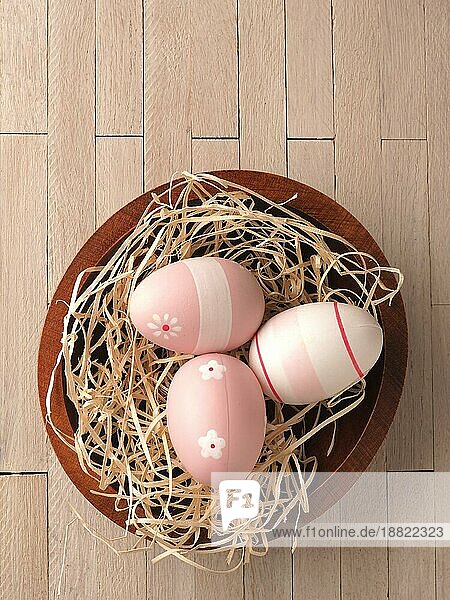 Drei rosa Ostereier in einem Nest auf einem Holztisch  traditionelles Osterkonzept