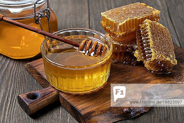 Gelber Honig und Honigwabenscheibe auf einem Holztisch