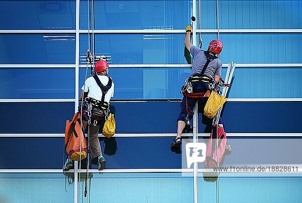 Zwei Bauarbeiter arbeiten in der Höhe an einem modernen kommerziellen Wolkenkratzer