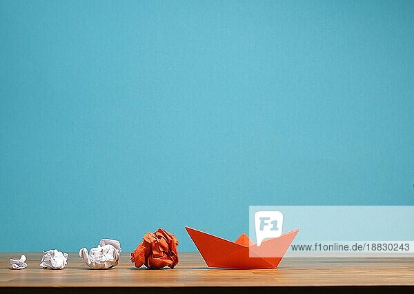 Teamwork Geschäftskonzept mit zerknittertem Papier und einem Papierboot auf einem hölzernen Bürotisch mit Platz für Text