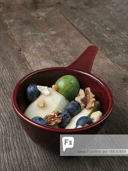 Biolebensmittel in einer Schüssel  gesunder Lebensstil  Früchte und Nüsse  vegetarisches Essen  Holztisch  Blick von oben