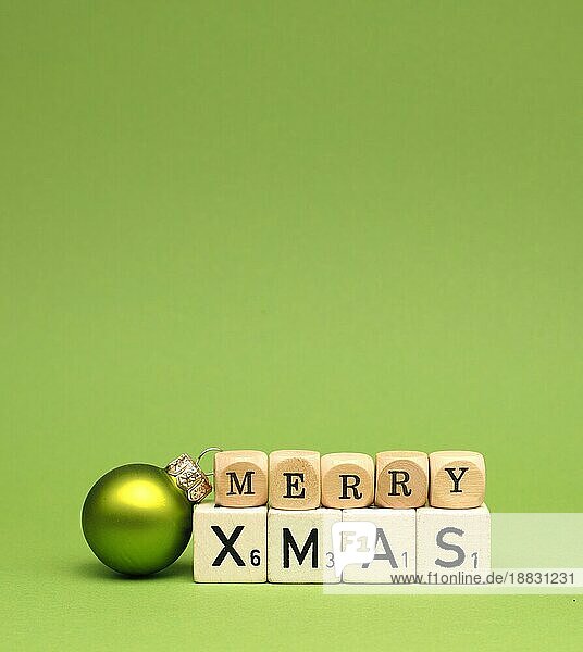 Holzklötze mit den Worten Frohe Weihnachten und einer Weihnachtskugel auf grünem Hintergrund  Platz für Text