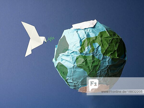 Abstrakter Globus aus zerknittertem Papier mit Origami Friedenstaube  globales Konzept für Freiheit und Frieden