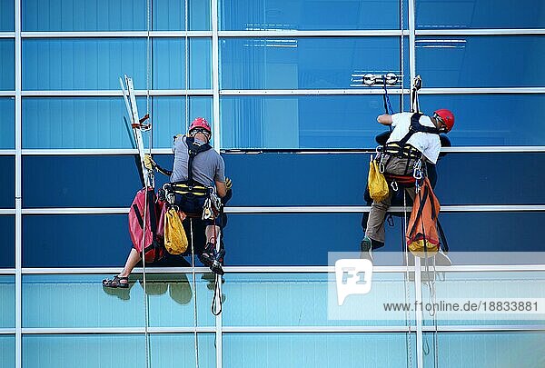 Zwei Bauarbeiter arbeiten in der Höhe an einem modernen kommerziellen Wolkenkratzer