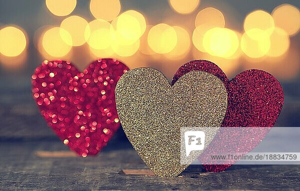 Drei glitzernde Herzformen mit verschwommenen Lichtern  Liebe oder Valentinstag Konzept Hintergrund