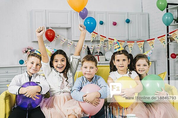Porträt Kinder sitzen Sofa halten Luftballons