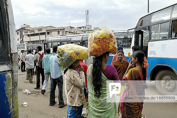 Blumenverkäufer warten auf den Bus mit Blumenstrauß auf dem Kopf in Bengaluru Bangalore  Karnataka  Südindien  Indien  Asien
