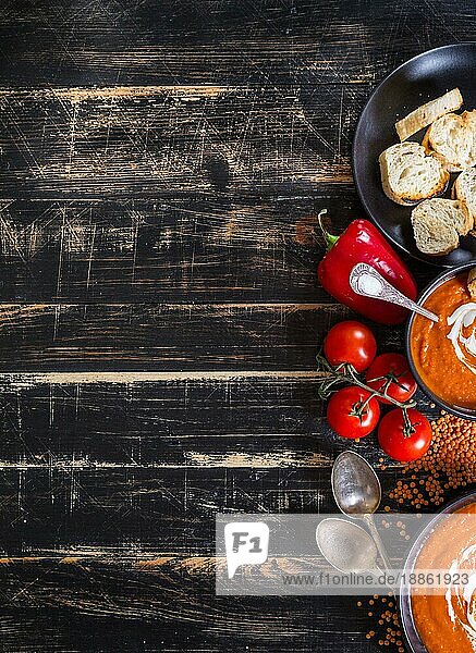 Leckere Kürbissuppe mit schwerer Sahne auf dunklen rustikalen Holztisch mit rotem Paprika  Toasts. Herbst/Halloween/Thanksgiving Tag Hintergrund. Ansicht von oben. Platz für Text