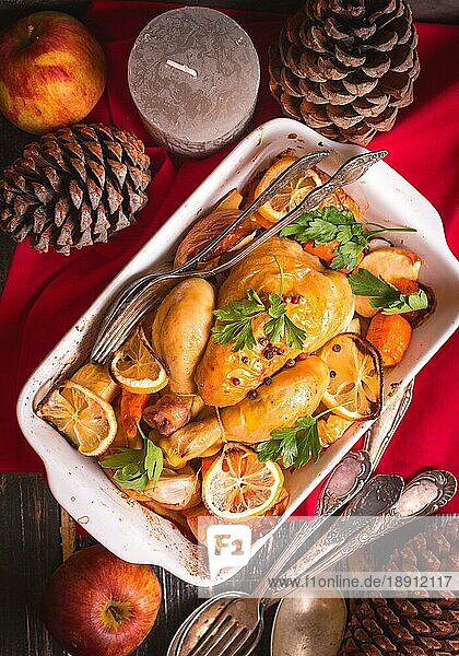 Gebratenes Huhn. Weihnachtsessen. Rustikaler Festtagstisch mit gebratenem Huhn  Gemüse  Äpfeln  dekoriert mit Kerzen  Vintage-Besteck. Weihnachten/Dankeschön-Essen. Festliches Abendessen. Ansicht von oben