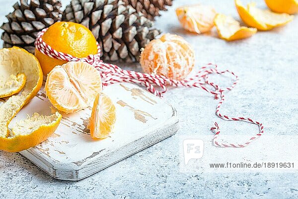 Winter weiß Weihnachten Hintergrund  Mandarinen  Tannenzapfen. Geschälte Mandarine  weißes Kochbrett. Neujahr Weihnachten festlichen Hintergrund. Winterferien. Dekoration  Feier Weihnachten. Platz für Text