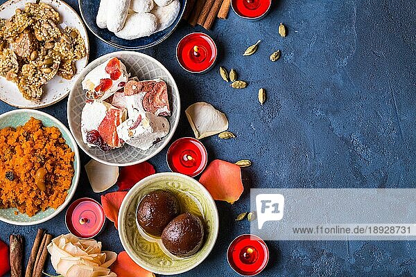 Indischer Diwali-Feierhintergrund mit traditionellen Süßigkeiten Gulab Jamun  Karotten Halwa  Snacks mit Kerzen  Blumen. Assorted indischen Desserts. Feiertag Festtagstisch. Diwali Einstellung. Platz für Text