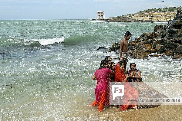 Touristen genießen das Baden im Meerwasser am Zusammenfluss der drei Meere Golf von Bengalen  Arabisches Meer und Indischer Ozean in Kanyakumari  Tamil Nadu  Südindien  Indien  Asien