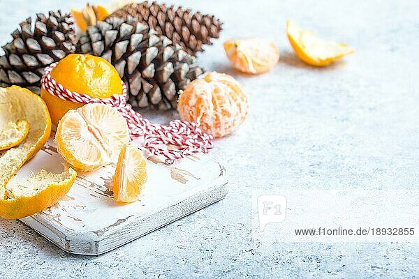 Winter weiß Weihnachten Hintergrund  Mandarinen  Tannenzapfen. Geschälte Mandarine  weißes Kochbrett. Neujahr Weihnachten festlichen Hintergrund. Winterferien. Dekoration  Feier Weihnachten. Platz für Text