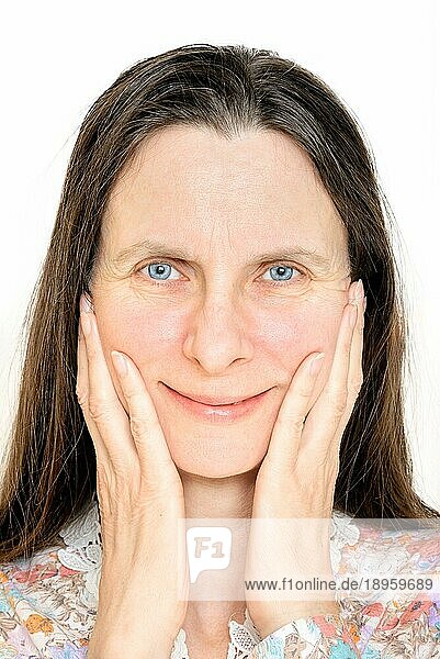 Porträt einer glücklich lächelnden reifen Frau  die ihre Hände auf dem Gesicht hat