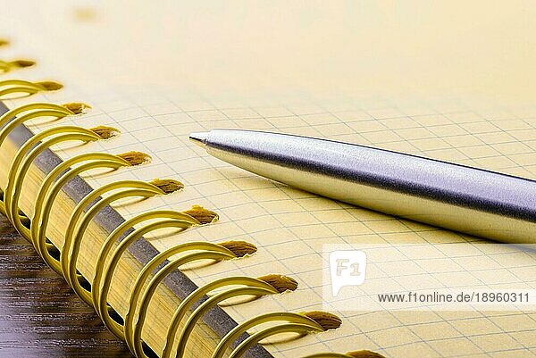 Makro der Spirale eines Notizbuchs aus gelbem Papier mit einem Metallstift