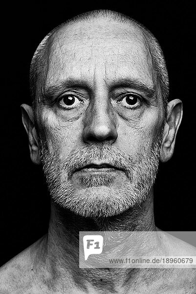 Dramatisches Schwarz Weiß Porträt eines erwachsenen Mannes mit traurigem Gesichtsausdruck auf schwarzem Hintergrund