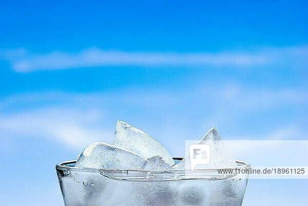 Eiswürfel in einem Glas mit frischem Wasser  bei bewölktem Sommerhimmel