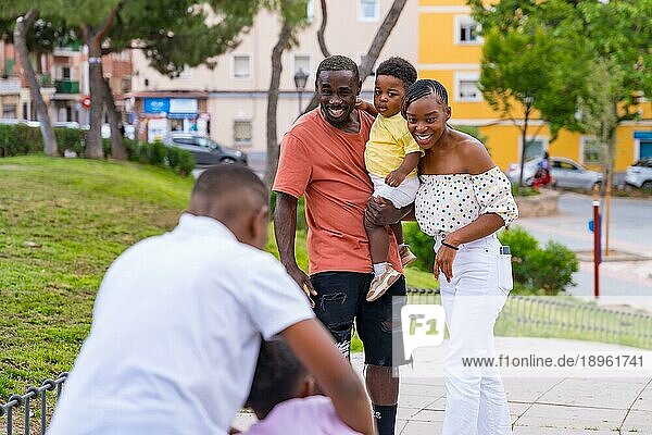 Afrikanische schwarze ethnische Familie  die Spaß mit glücklichen Kindern zusammen im Stadtpark hat
