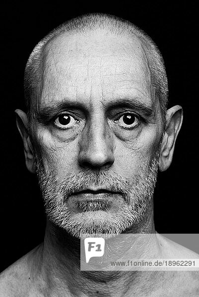 Dramatisches Schwarz Weiß Porträt eines erwachsenen Mannes mit traurigem Gesichtsausdruck auf schwarzem Hintergrund