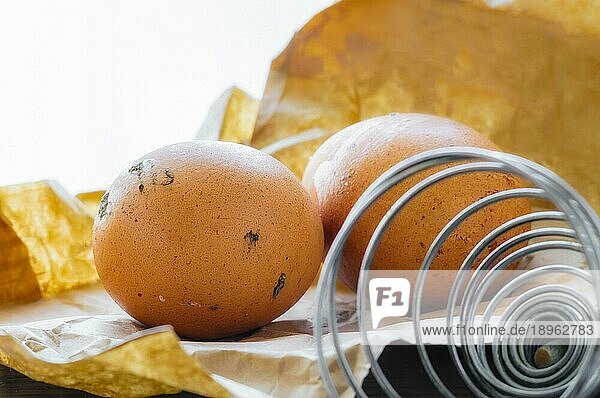 Zwei frische Eier  gerade gelegt  auf einer braunen Papiertüte mit einer Spiralpeitsche
