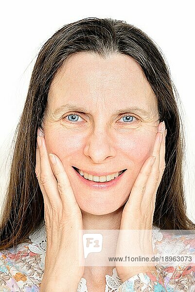 Porträt einer glücklich lächelnden reifen Frau  die ihre Hände auf dem Gesicht hat
