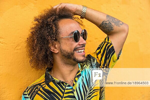 Mann mit Afrohaar im Sommer in einem Palmenhemd auf gelbem Hintergrund