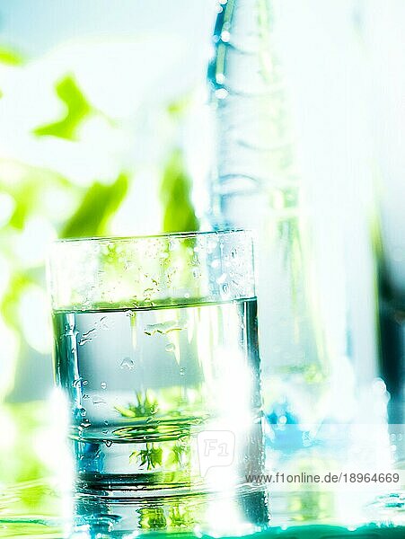Frisches und kaltes Wasser in einem Glas. Die Transparenz wird durch das Gegenlicht und den Unschärfeeffekt im Hintergrund verstärkt