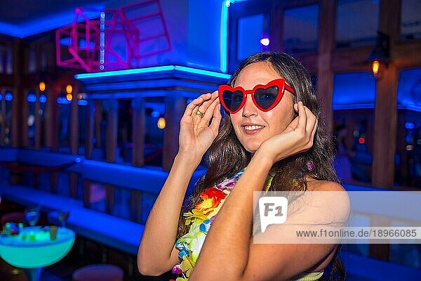 Attraktive lateinamerikanische Frau auf einer Nachtparty in einer Disco mit Gläsern voller Herzen
