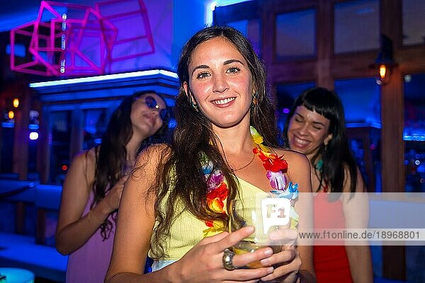 Attraktive Frau lächelnd mit einem Glas Alkohol in einem Nachtclub bei einer Nachtparty