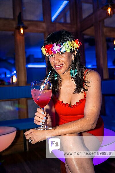 Porträt der attraktiven lateinischen Frau lächelnd mit Glas Alkohol lächelnd auf einer Nachtparty