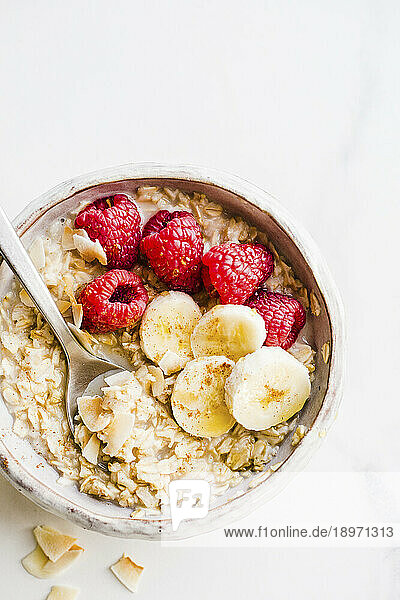 Oatmeal Bowl with raspberries  bananas and coconut flakes