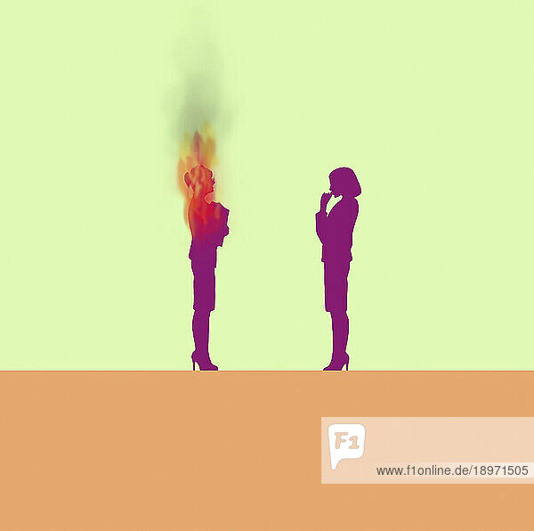 Frau schaut auf brennende Geschäftsfrau