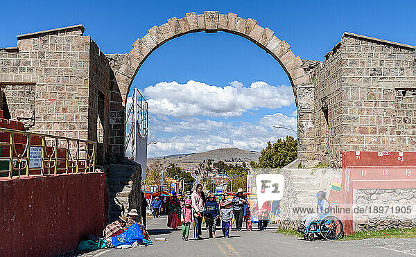 People walking under an arch  across the Peru Bolivia border from Puno in Peru to Copacabana in Bolivia.