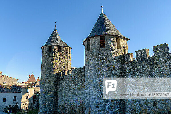 The Château Comtal  Count’s Castle  is a medieval castle in the Cité of Carcassonne  tall towers and wall  and a bridge to a fortified gate.