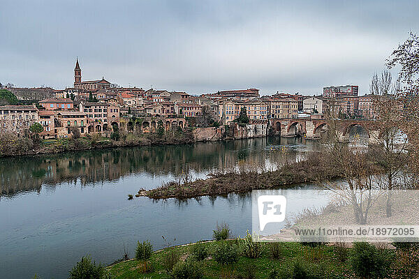 View of Albi  the city and historic buildings from the River Tarn  the Pont Vieux and an island in the stream.