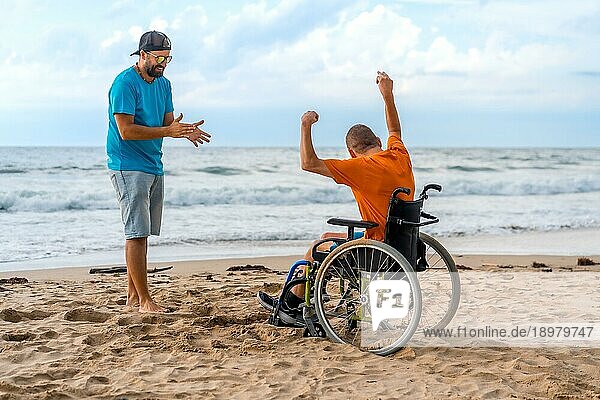 Porträt einer behinderten Person im Rollstuhl am Strand  die lacht und Spaß am Meer hat