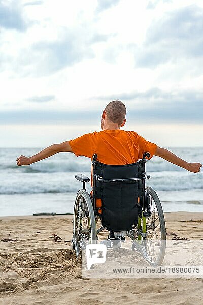 Eine behinderte Person in einem Rollstuhl auf dem Rücken am Strand
