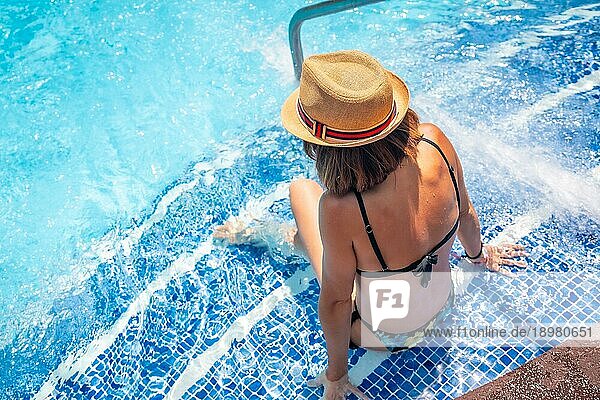Frau mit Hut im Pool in einem Kurort im Urlaub. Sommer entspannende Konzept