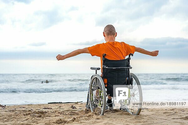 Eine behinderte Person in einem Rollstuhl auf dem Rücken am Strand