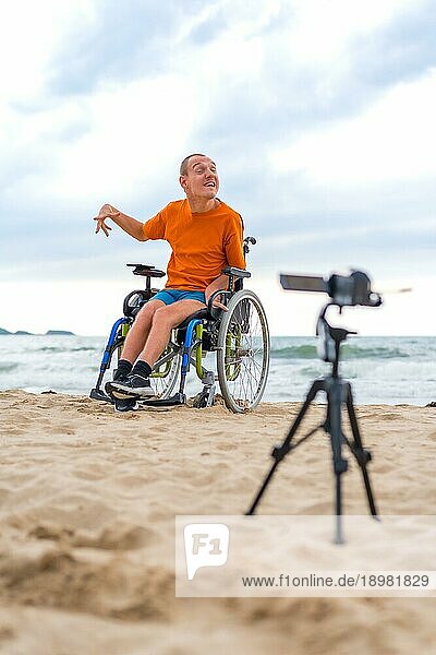 Eine behinderte Person im Rollstuhl nimmt am Strand ein Video auf