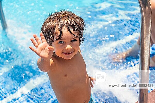 Zweijähriger Junge genießt den Sommer in einem Schwimmbad  lächelt im Urlaub vom Wasser