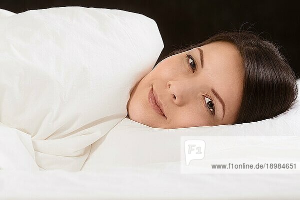 Attraktive junge Frau  die einen friedlichen Schlaf genießt und mit einem heiteren Ausdruck im Bett liegt und träumt