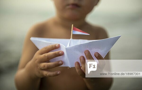 Kleines Kind hält Papierboot in der Hand