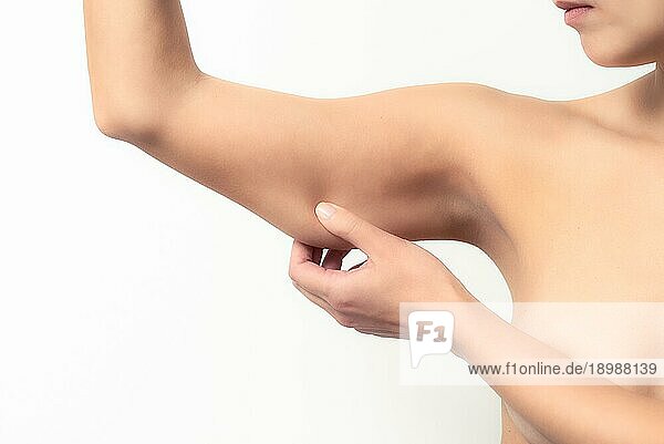 Frau testet den schlaffen Muskel unter ihrem Arm  indem sie ihn mit der Hand nach unten zieht  um den Muskeltonus oder die Gewichtszunahme zu überprüfen