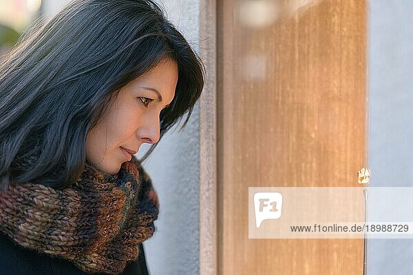 Brünette attraktive Frau beim Einkaufen im Winter  Blick ins Schaufenster  Seitenansicht