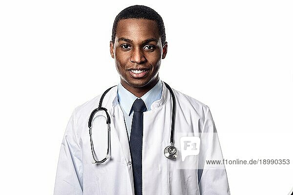 Attraktiver  selbstbewusster afrikanischer Arzt mit weißem Kittel und Stethoskop  der mit ernster Miene in die Kamera schaut  Oberkörper vor weißem Hintergrund