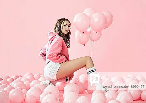 Junge trendige Frau posiert mit rosa Luftballons auf rosa Hintergrund. Pop Art. Feiern  festlich  Spaß Konzept